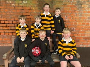 Group of schoolchildren in uniform sitting outdoors.