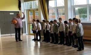 Children standing in line listening to teacher in school classroom.
