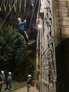 A person engaging in outdoor climbing at Inchmarlo Adventure Park, surrounded by forest.