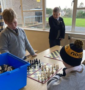 Two boys playing chess indoors at Inchmarlo, fostering strategic thinking and social skills.