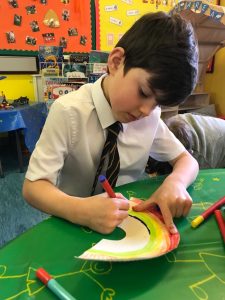 Young boy drawing colorful artwork at Inchmarlo childcare.