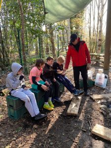 Children sitting outdoors with instructor in woodland environment at Inchmarlo.