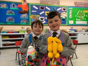 Smiling children holding colorful plush toys at Inchmarlo School classroom.