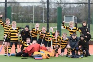 Group of children playing tennis outdoors in sports uniforms.