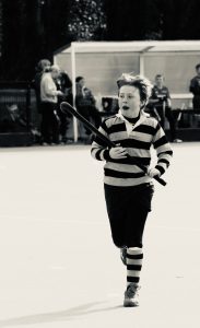 Young boy skating outdoors on ice at Inchmarlo ice rink, Scottish scenery in background.