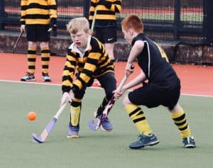 Children playing hockey on school field at Inchmarlo campus, active sports activity, outdoor recreation.