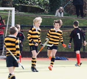Youth hockey players in striped uniforms on a field during a game.