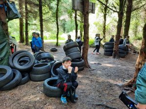 Children enjoying outdoor adventure play with tires in a wooded area at Inchmarlo.
