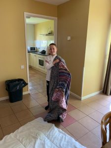 Young girl holding colorful quilt in cozy home interior.