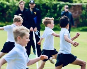 Children running and playing on a lush green field at Inchmarlo school sports day.