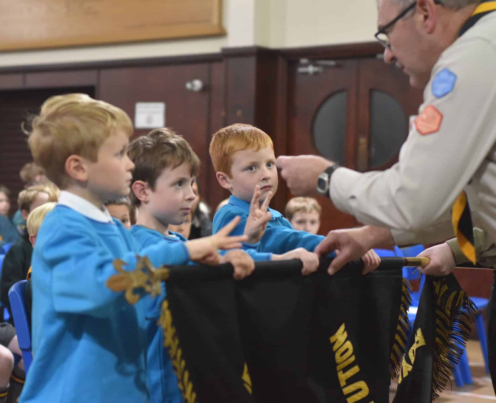 Young scouts receiving recognition and badges in a school or community event.