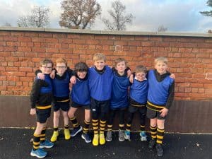 Group of children in soccer uniforms standing outdoors against a brick wall.