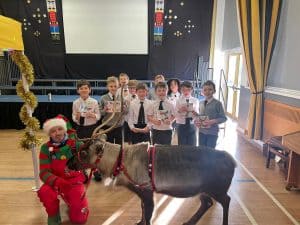 Young students with Christmas cheer at Inchmarlo care home, celebrating holiday festivities in a festive setting.