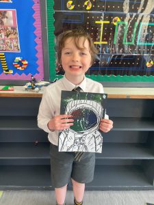 Young boy holding artwork at Inchmarlo School.