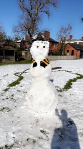 Snowman at Inchmarlo golf course, dressed with scarf and hat on snowy landscape.