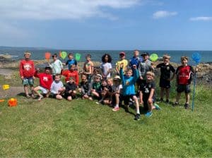 A group of children and adults enjoy a day outdoors by the seaside at Inchmarlo.