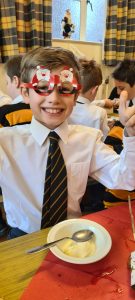 Child with Christmas-themed face paint smiling in classroom.
