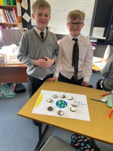 Two students presenting a science project with solar system models in classroom.