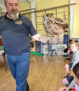 Man holding an owl during a wildlife educational session at Inchmarlo, Scotland.