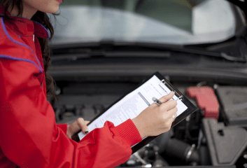 Technician inspecting car engine during vehicle service.