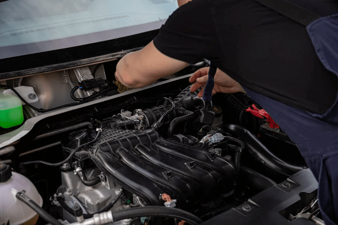 Engine repair technician inspecting a vehicle engine in Clarkrange, TN.