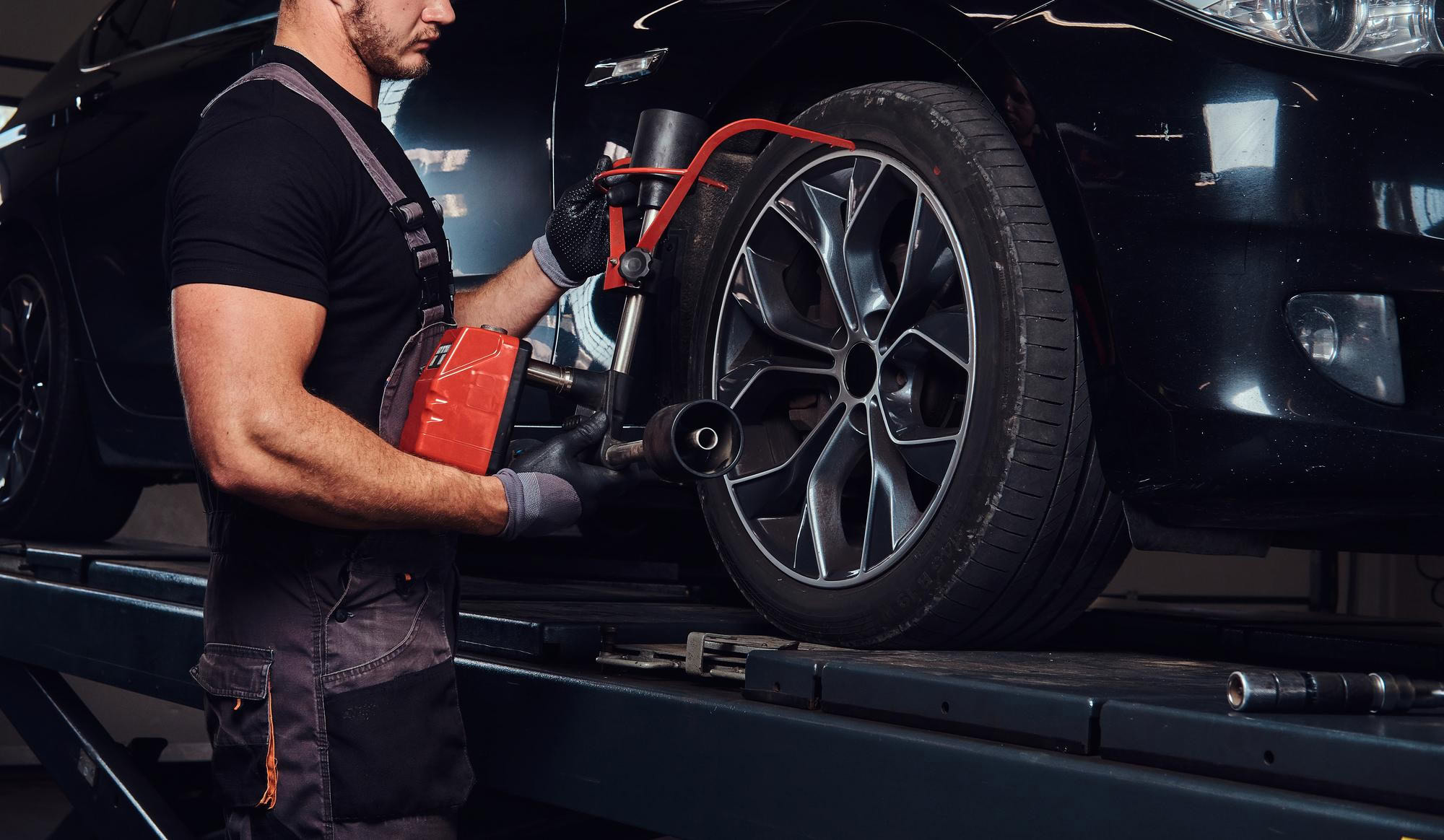 Technician checking car brakes and suspension system for signs of wear.