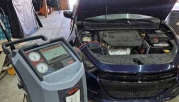 Car air conditioning system being serviced with diagnostic equipment at Izzy's Blue Auto.