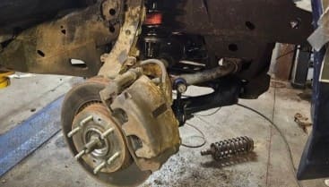 Car suspension and brake system being repaired in auto shop.