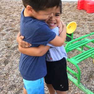 Happy children hugging outdoors at Jarrell Montessori preschool.