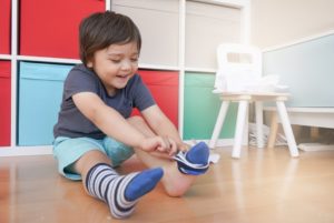 Colorful Montessori classroom with young boy playing on the floor with socks and toys.