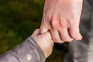 Close-up of an adult and child holding hands, symbolizing care and connection.