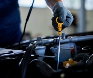 Close-up of a mechanic using a screwdriver on a car engine.