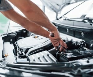 Mechanic inspecting car engine for maintenance or repair.