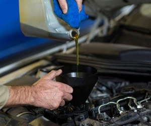 Mechanic pouring engine oil during oil change at JC Auto Repair.