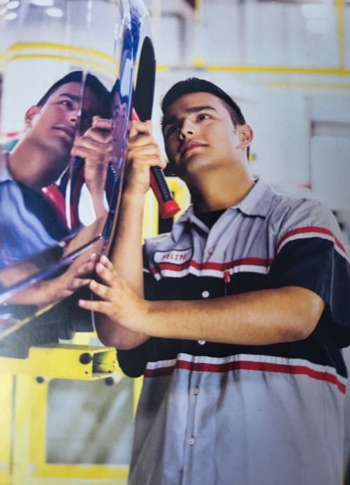 Auto repair technician repairing a car's body panel with a screwdriver.