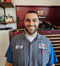 Auto repair technician smiling in workshop, providing quality car services.