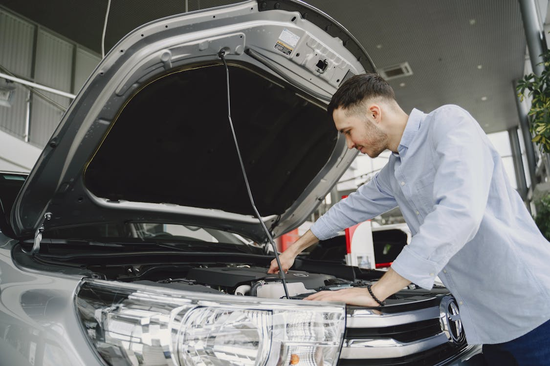 Car mechanic inspecting engine for general maintenance and longevity.