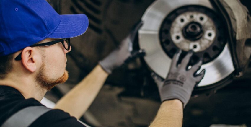 Technician inspecting brake pads on a vehicle's wheel for safety and performance.
