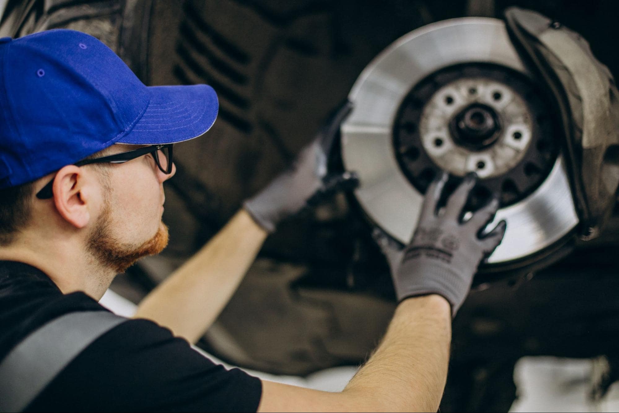 Technician inspecting brake pads on a vehicle's wheel for safety and performance.