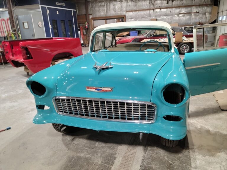 Restored vintage blue and white classic car in workshop.