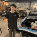 Auto restoration workshop with a young technician working on a classic car.