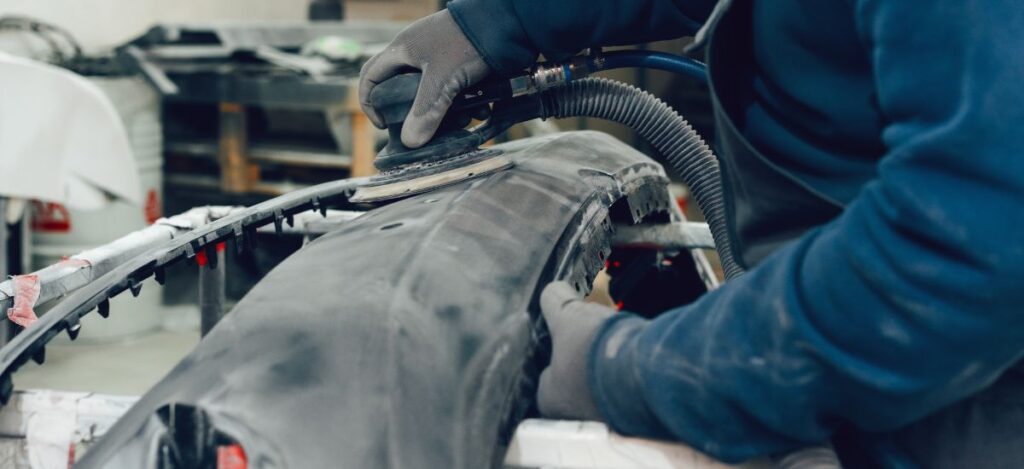 Technician repairing car body with advanced tools in auto restoration shop.