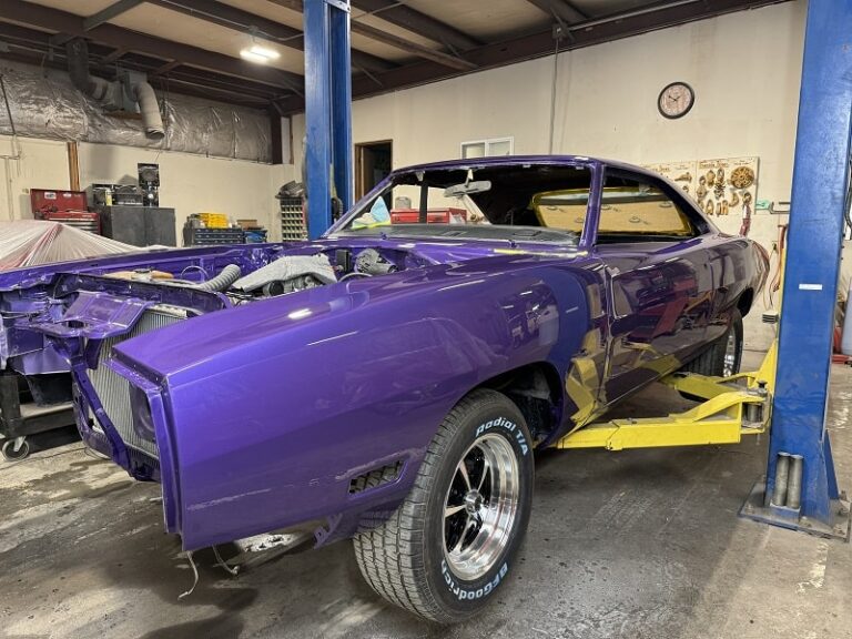 Restoring a vintage purple muscle car on a hydraulic lift at John's Auto Restorations.