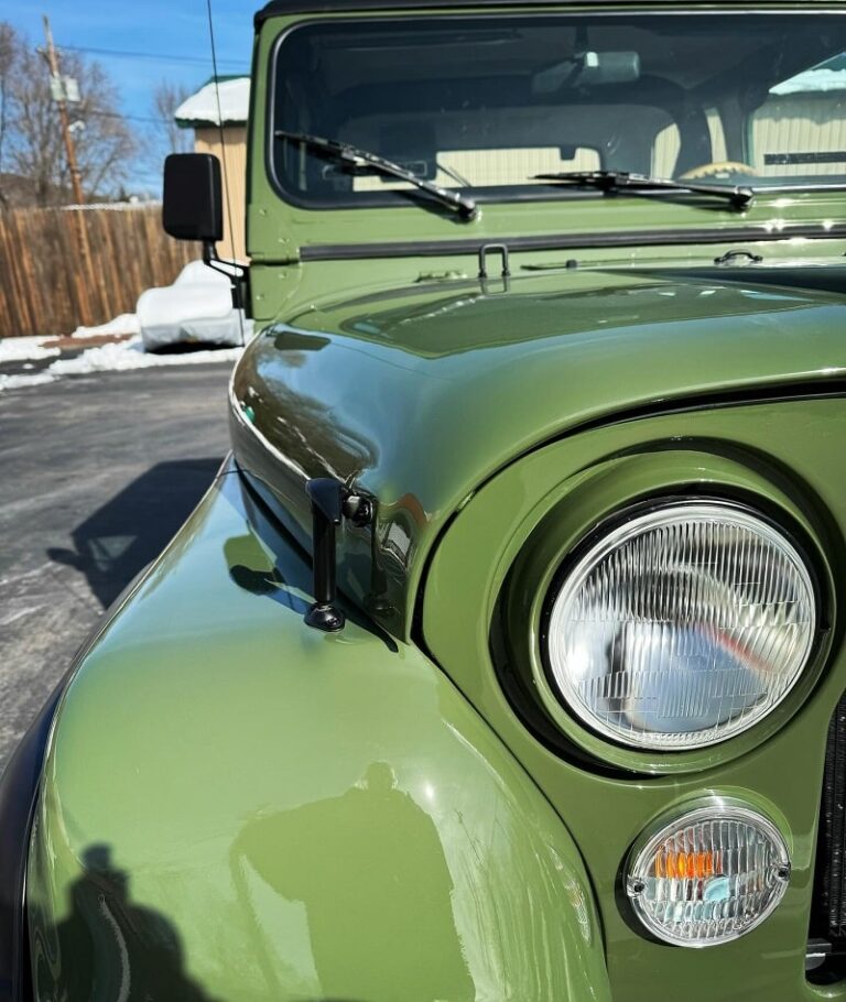 Classic green Jeep with round headlights and vintage design.