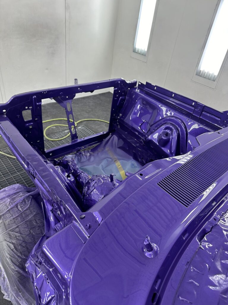 Automotive restoration of a classic car chassis in vibrant purple.
