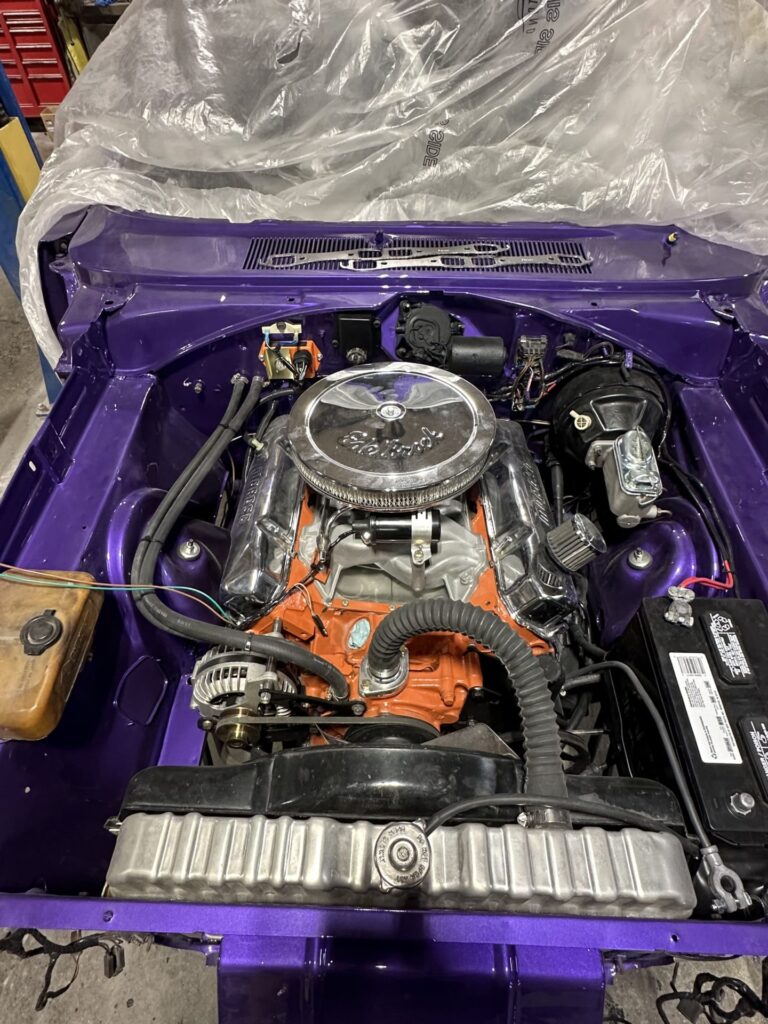 Engine bay of a restored classic car with vibrant purple paint.