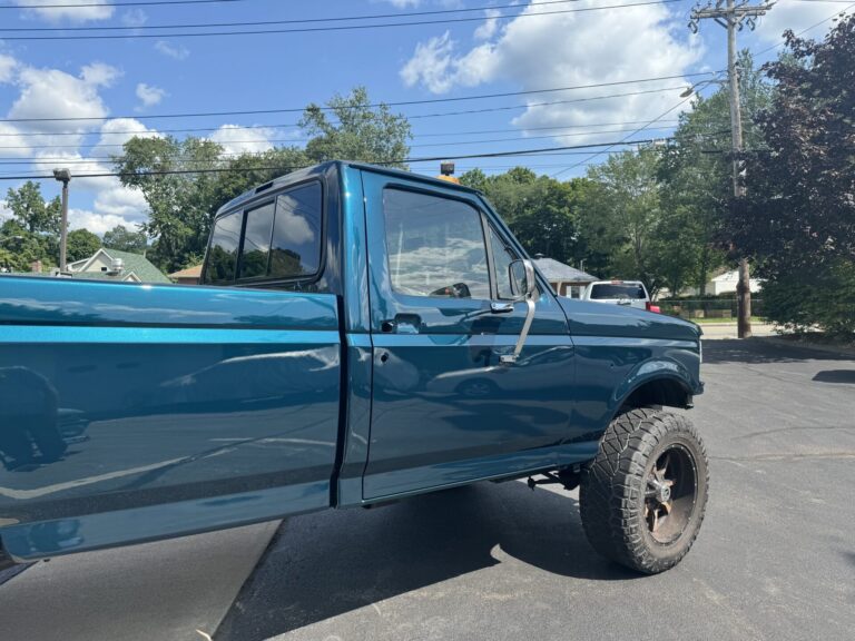 Custom blue pickup truck with lifted suspension at John's Automotive.
