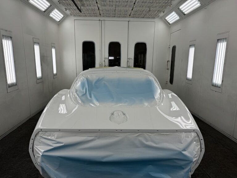 White sports car in paint booth during restoration process.