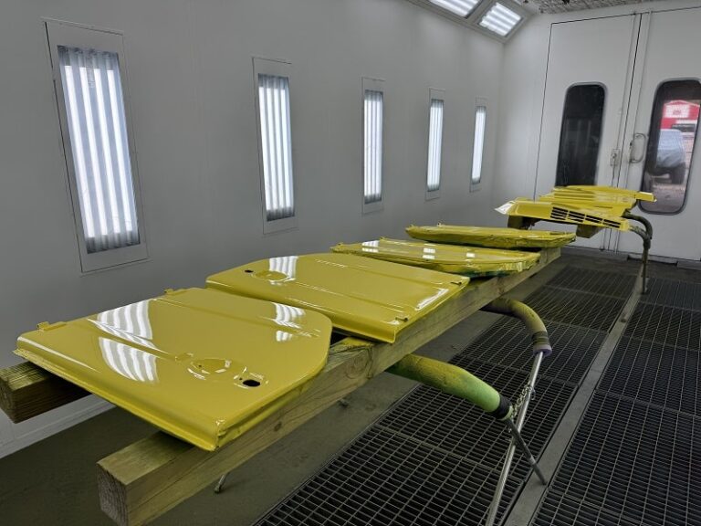 Freshly painted yellow car hoods in auto body shop for restoration.