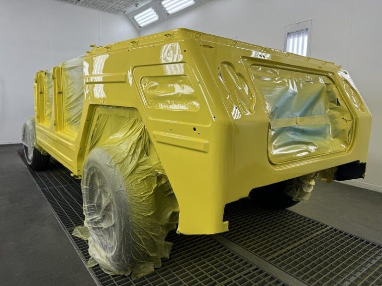 Vehicle body being painted in a professional auto shop.